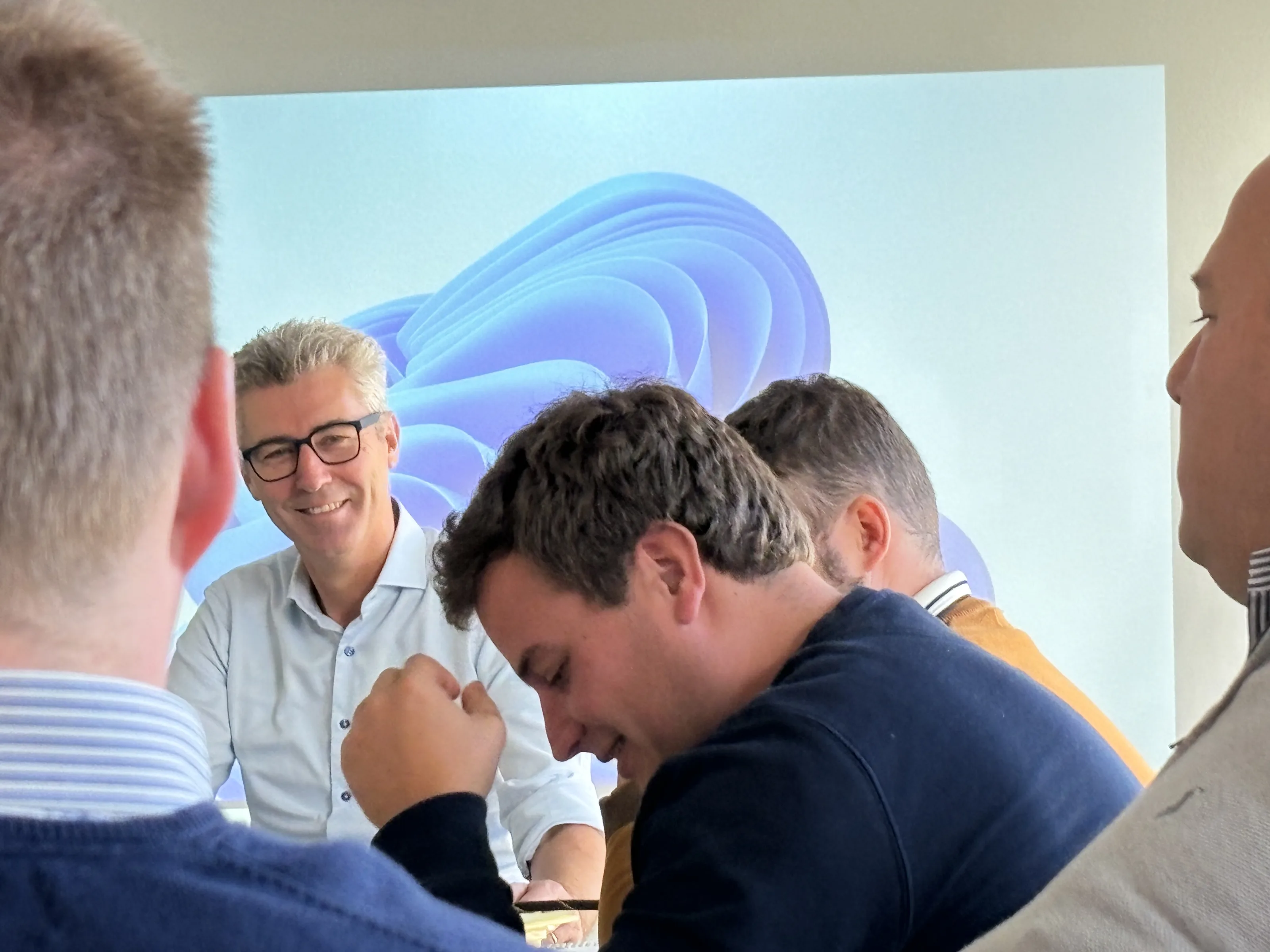Een begeleider in gesprek met deelnemers aan tafel